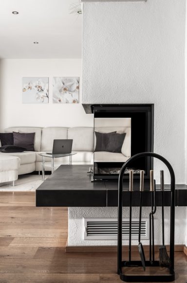Moderne Wohnung mit schwarzem Kamin, hellem Sofa und minimalistischer Einrichtung.